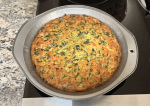 A flat lay of ingredients for a tortilla quiche bake, including tortillas, eggs, shredded cheese, chopped vegetables, and seasonings arranged on a kitchen countertop