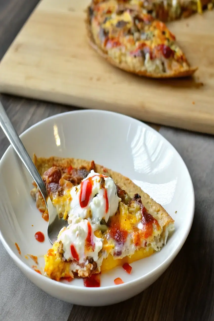 Close-up of tortilla quiche slice in bowl topped with cottage cheese and hot sauce