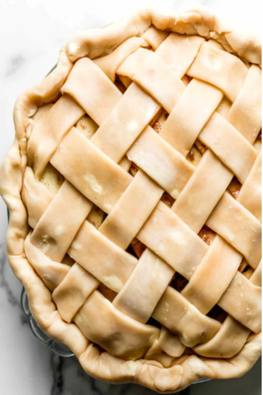 Raw apple pie with a neatly woven lattice crust in a glass pie dish
