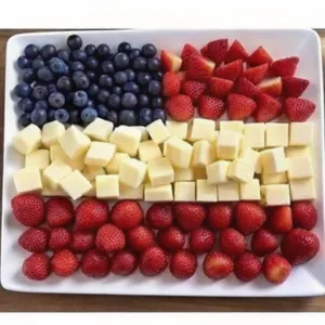A square white plate arranged with blueberries, strawberries, and white cheese cubes to look like the United States flag.