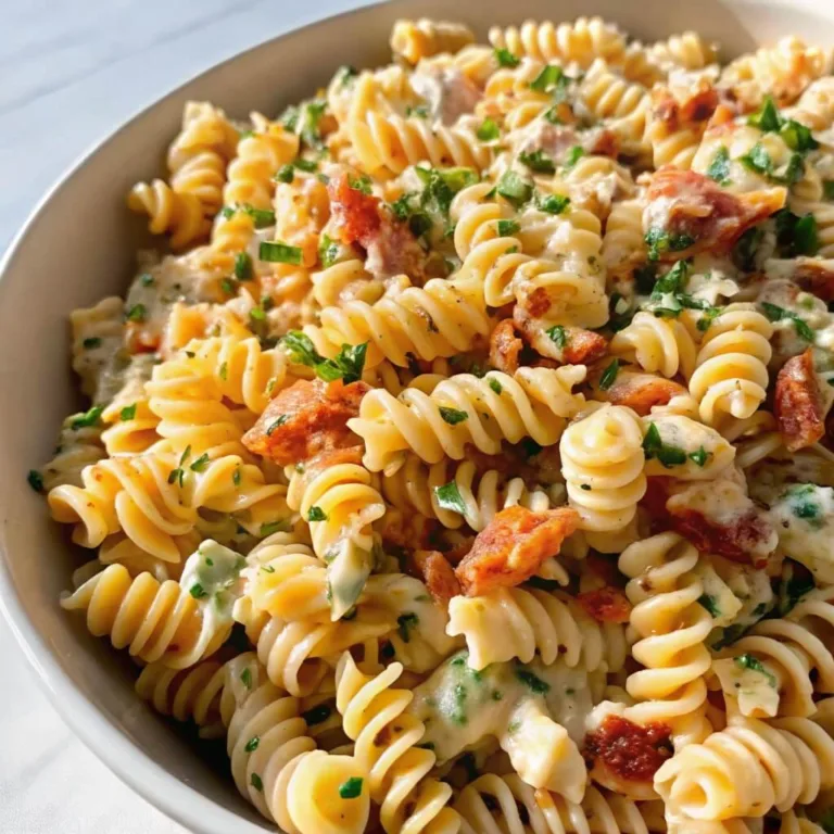 Macro shot of rotini pasta salad showing the creamy texture and large pieces of savory bacon.