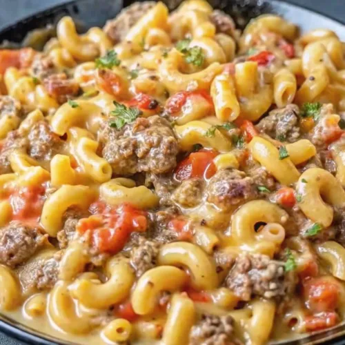 Close up of a creamy beef goulash skillet with elbow macaroni pasta, seasoned ground beef, and diced tomatoes.