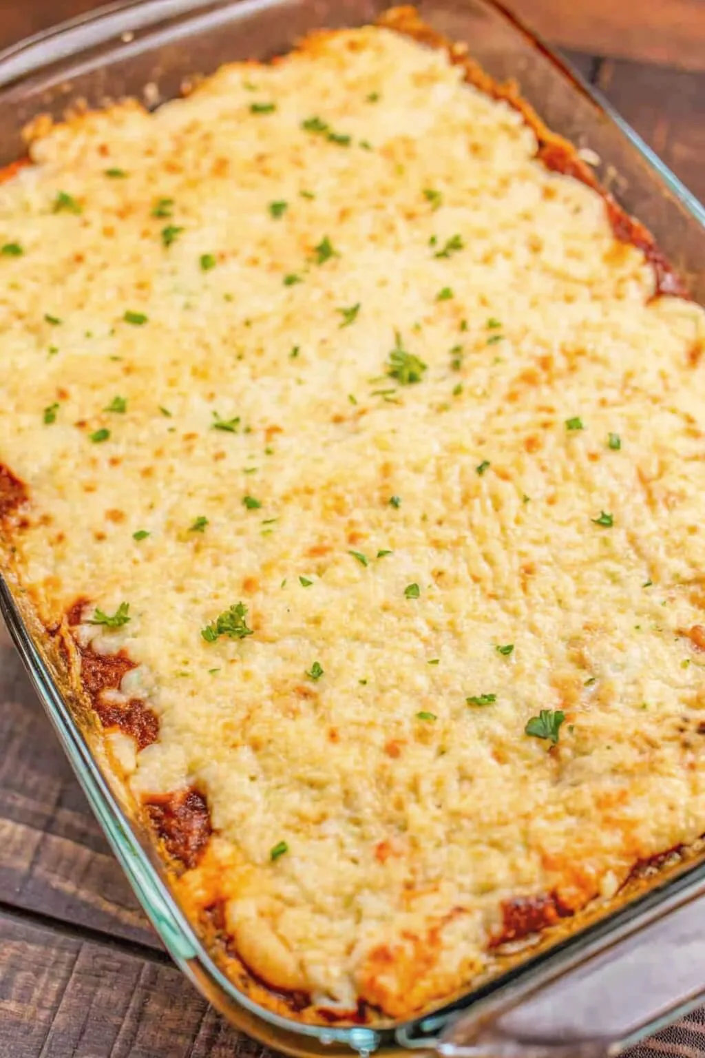 A glass baking dish filled with a bubbling Shepherd's Pie casserole, featuring a thick layer of melted, golden-brown cheese and a rich meat sauce border.