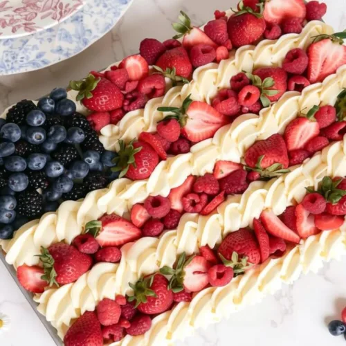 An overhead view of an easy 4th of July flag cake made with blue berries for the stars and alternating rows of red berries and piped white frosting.