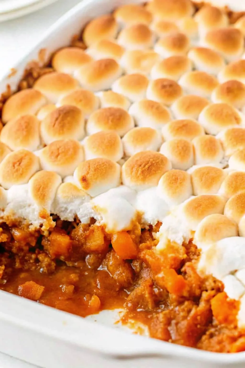 Sweet potato casserole with a toasted marshmallow crust inside a white ceramic baking dish.