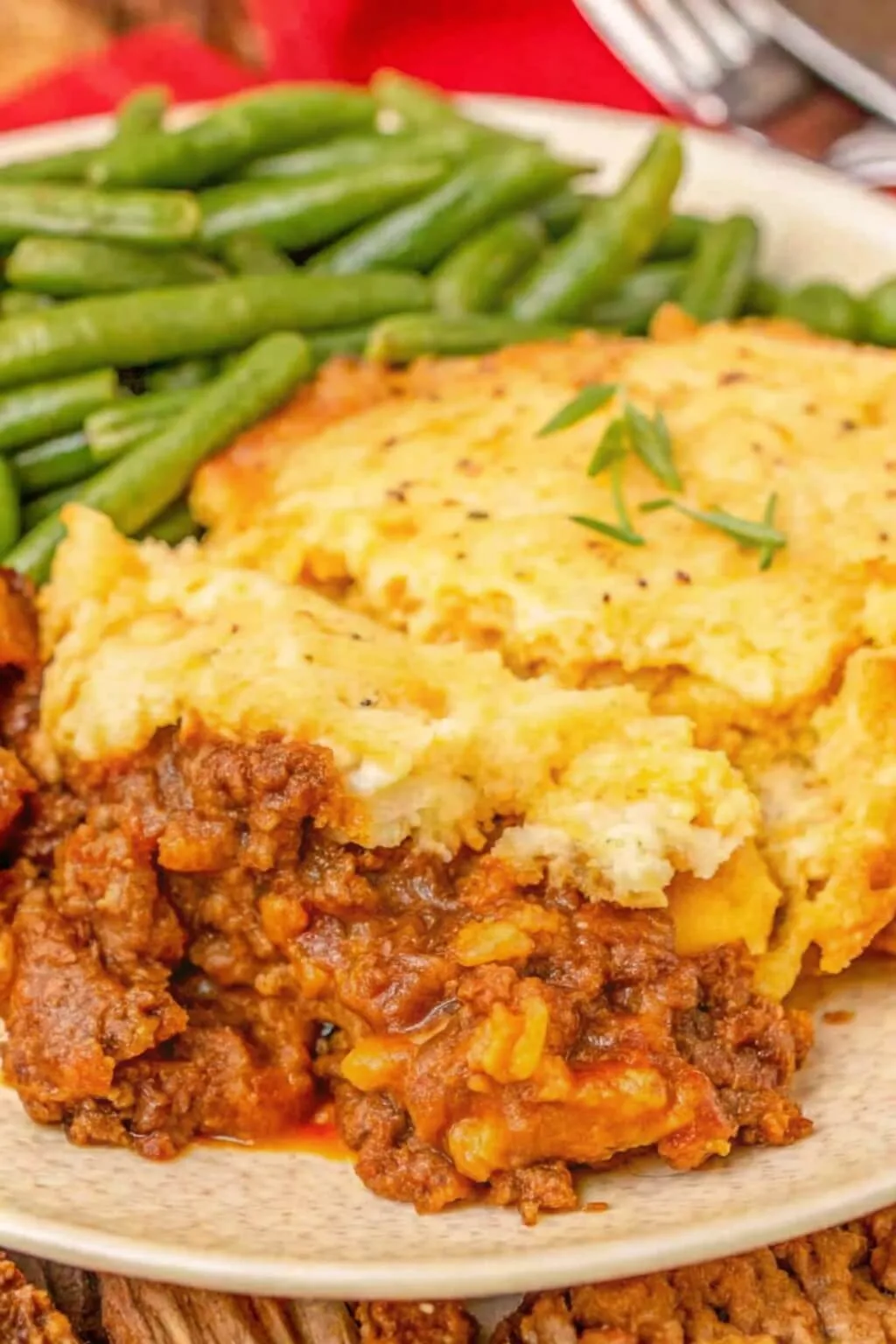 A close-up shot of a plated serving of Shepherd's Pie showing the hearty ground beef filling and a thick, creamy mashed potato and cheese topping.