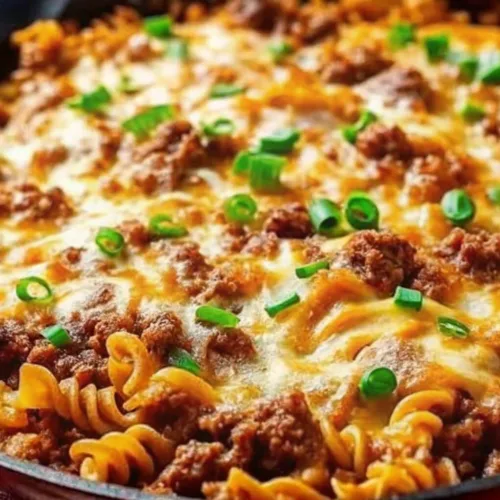 One pot cheesy ground beef and rotini pasta skillet bake garnished with green scallions.