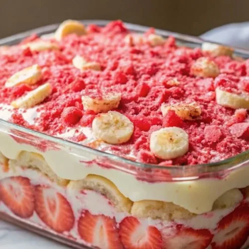A glass baking dish filled with a layered strawberry banana icebox cake showing fresh strawberry slices along the side.