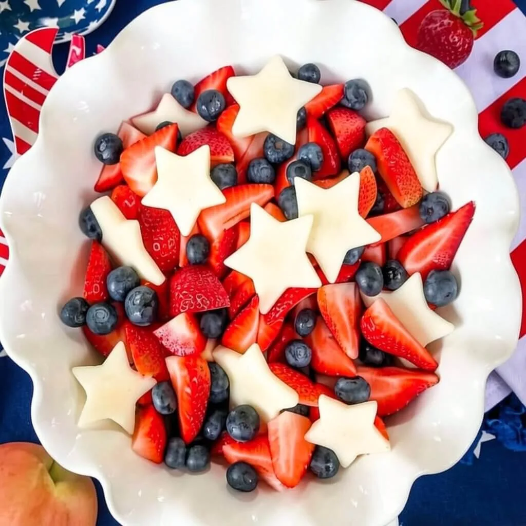 Top down view of a large white bowl filled with a red white and blue patriotic fruit salad for a summer cookout.