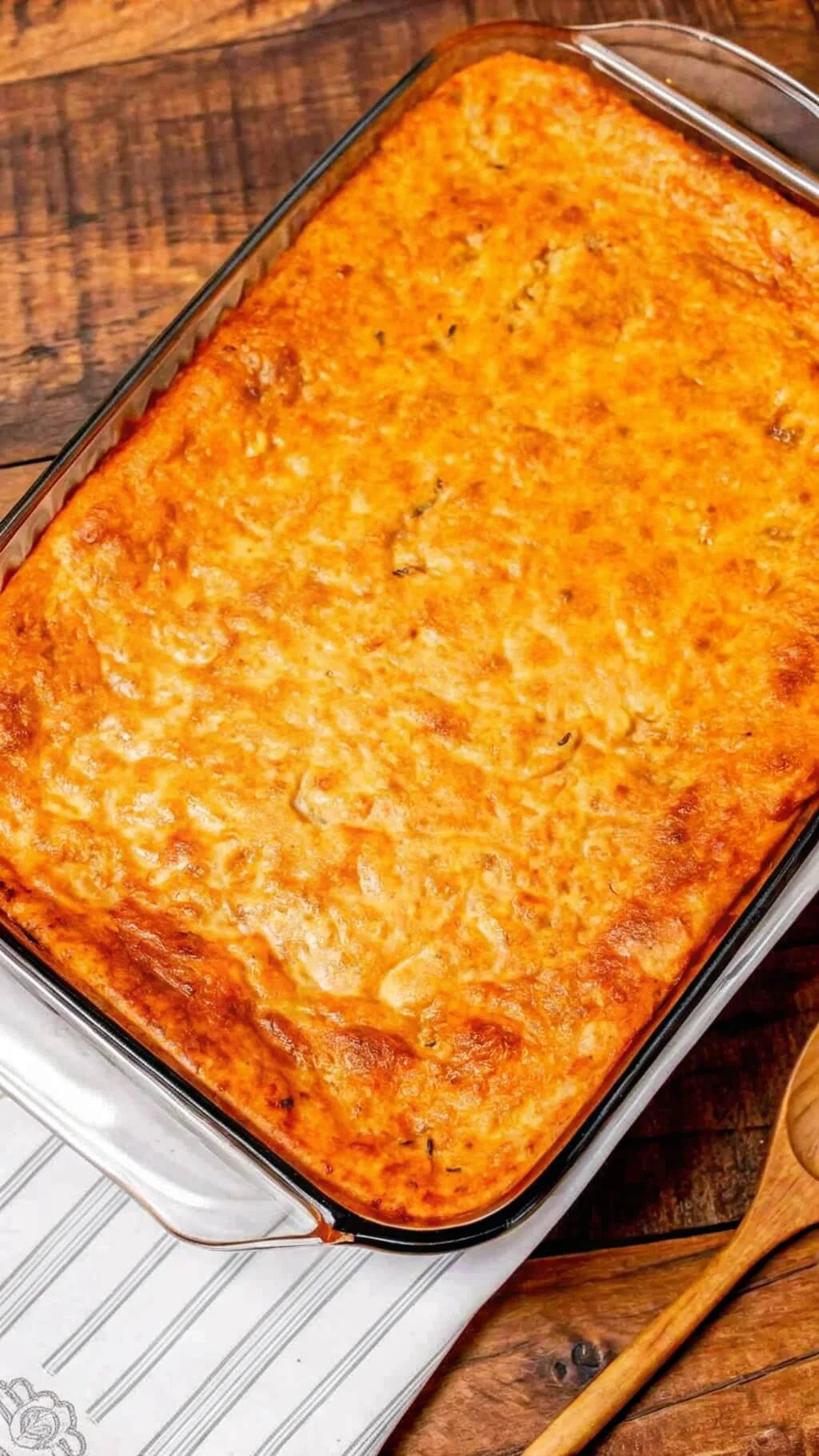 A top-down view of a full glass baking dish containing Million Dollar Spaghetti with a perfectly browned, bubbly cheese top.