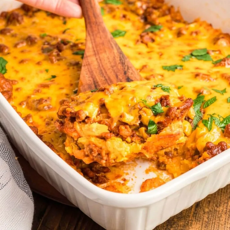 A wooden spoon scooping a portion of an easy Mexican cornbread casserole topped with melted cheddar cheese and fresh cilantro from a white fluted dish.