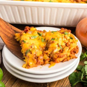 A served slice of a ground beef tamale pie recipe on a white plate, highlighting layers of sweet cornbread, seasoned meat filling, and melted cheese.